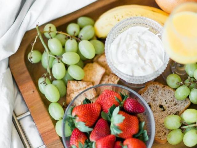 Um café da manhã de rainha com muitas frutas, pães e doces deliciosos.