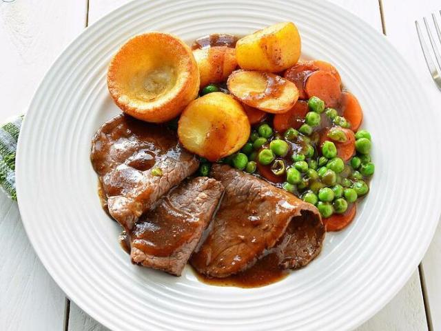 Assado acompanhado de pão de ovos, batatas, vegetais e molho gravy