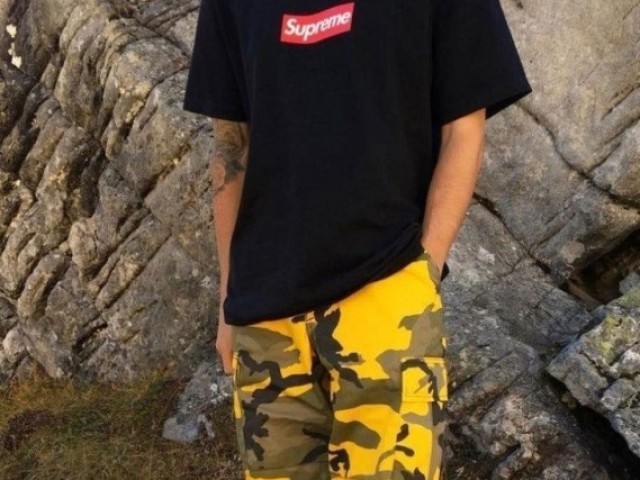 Uma blusa da supreme e a calça amarelo camuflada