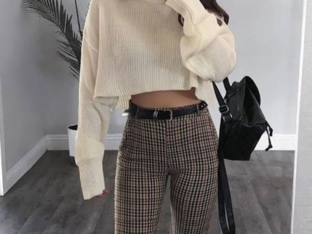 cropped de manga longa, com uma calça skinny xadrez, uma mochilinha e nos pés uma botinha preta