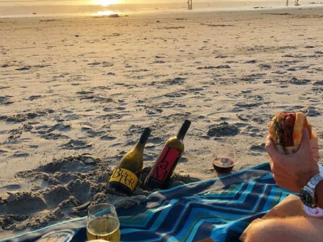 Um picnic, só que na praia com um bom vinho branco, sanduíches e talvez um banho de mar ao por do sol.