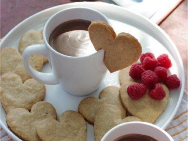 Um delicioso café com leite, pequenos biscoitos em formato de coração, e framboesas.