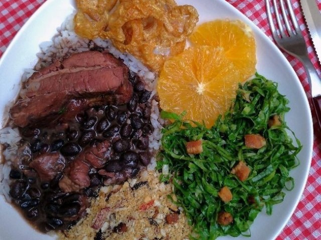 Feijoada, farofa, laranja e uma salada de couve e tomate