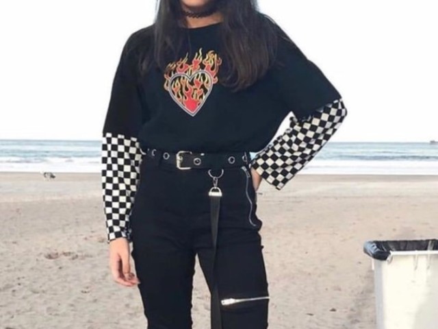 Uma blusa preta larga, com uma blusa de manga longa xadrez por baixo, uma calça jeans preta, um cinto preto e um tenis vans cano alto...