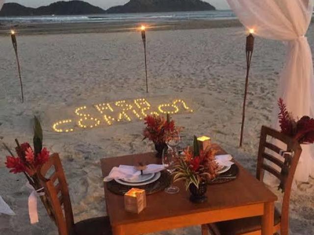 Na praia, com luzes, e um jantar tropical.