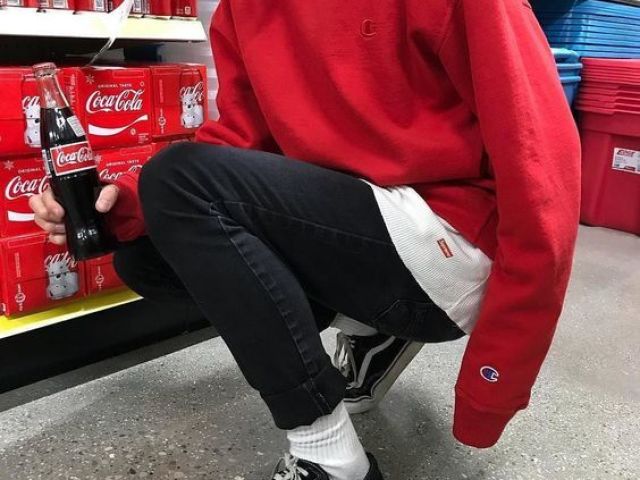 Um moletom vermelho, uma blusa branca, uma calça jeans preta e um vans.