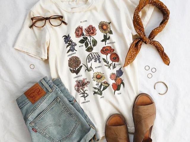 Uma blusa branca com desenho de flores e com um shorte jeans e uma sandália marom com uma bandana laranja e um óculos laranja sem gral...