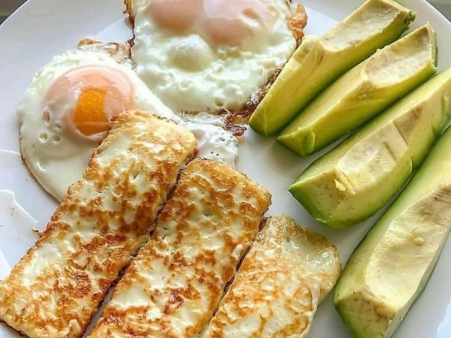 Um delicioso prato com ovos fritos, abacate, e homeletes com queijo.