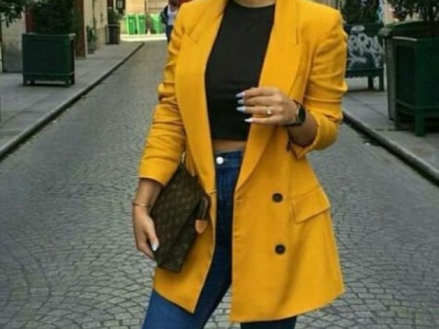 1 top preto, com casaco amarelo e calça escura.