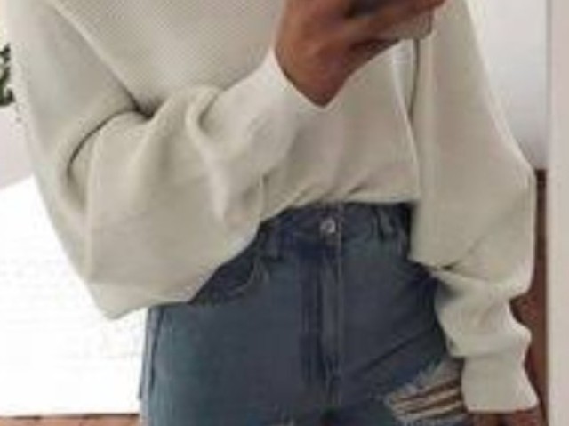 Uma blusa branca de mangas,uma calça jeans azul rasgada e um tênis branco