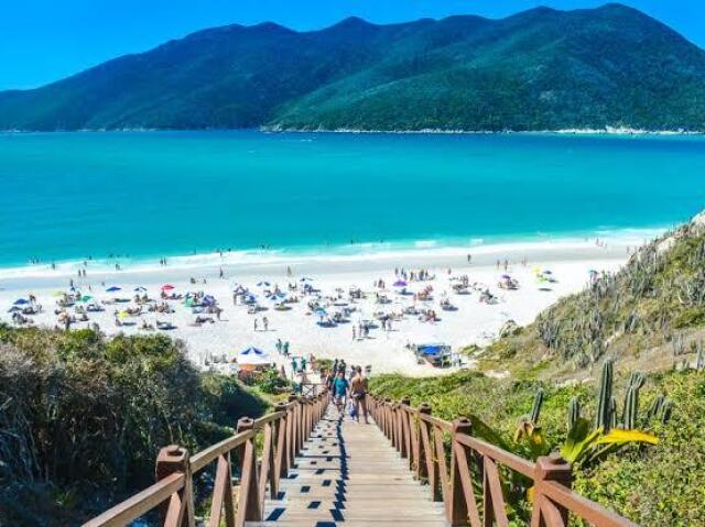 Um lugar com praia, bem calor, com um mar imenso para curtir umas ondas ou para tomar uma água de côco enquanto eu fico debaixo do meu guarda sol.