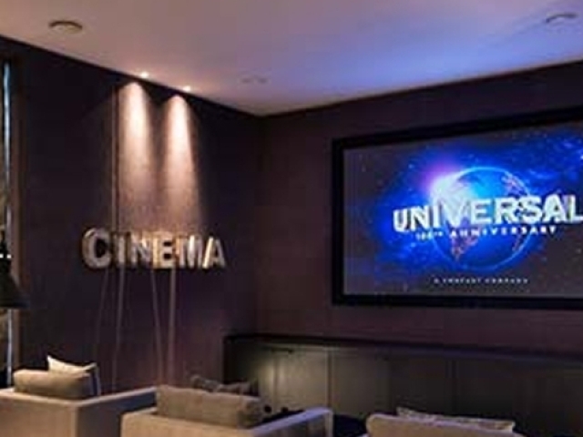 uma sala de cinema com uma tv bem gigante