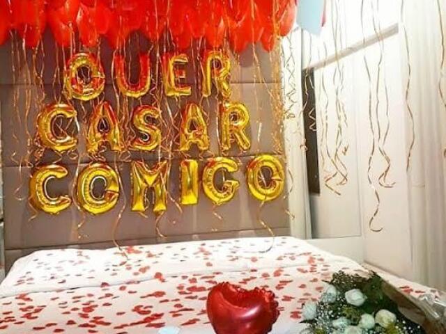 Uma surpresa com pétalas de rosa e velas na cama.