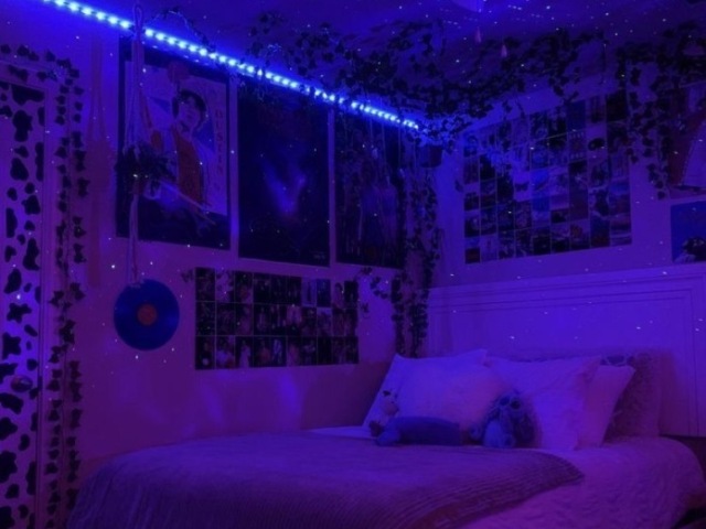 ♡ Um quarto branco também, mais cheio de coisas mas paredes. Parece um estereotípico de Tiktoker. Luzes LED, um CD na parede, vinhas pela porta e vários posters e capas de albums na parede. Uma mesa com uma luzinha de lupa para fazer TikTok’s ou outra coisa.