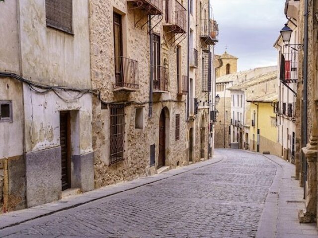 A rua de paralelepípedos com edifícios antigos.