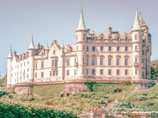 Um castelo grande, porém aconchegante, sua cor é apenas branca, e seu telhado é pontudo.
