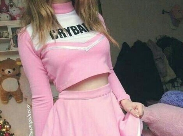 Conjunto rosa que parece de líder de torcida, escrito "Cry Baby" e carregando uma bolsinha.