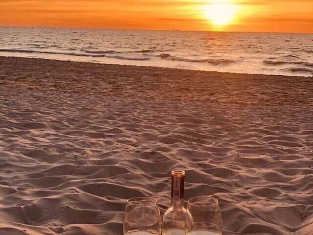 A praia no final do dia com uma brisa fresca uma taça de vinho e o colo quente do seu amor