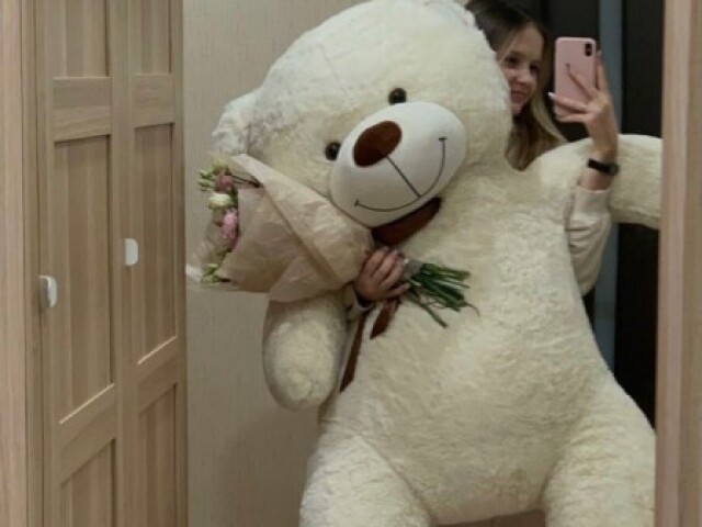 Um urso gigante e um buquê de Flores.