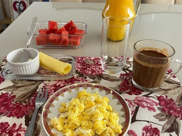 Ovos mexidos, café com leite, suco de laranja, queijo e melancia.