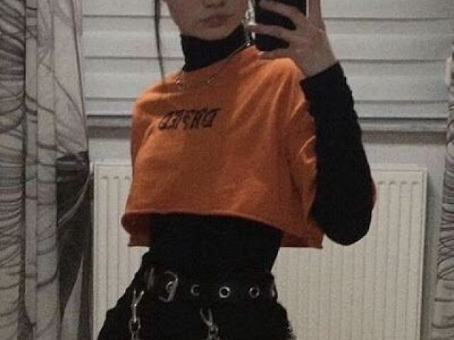 Um "Cropped " laranja, com uma camiseta preta por baixo e uma calça jeans preta.