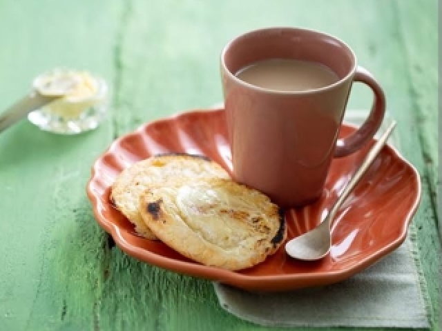 Um simples café da manhã com um café com leite e um pãozinho.