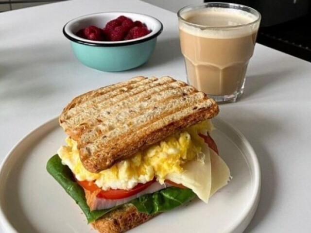 Sanduíche com ovo, frutas vermelhas e leite com uma gota de café