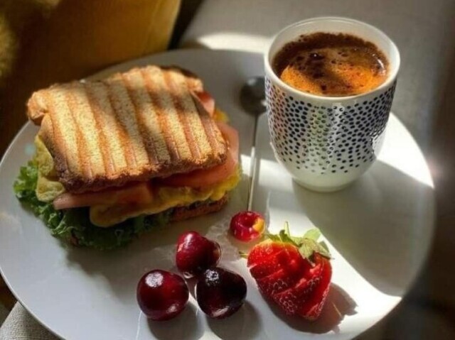 Um misto quente com um café/capuccino e frutas vermelhas