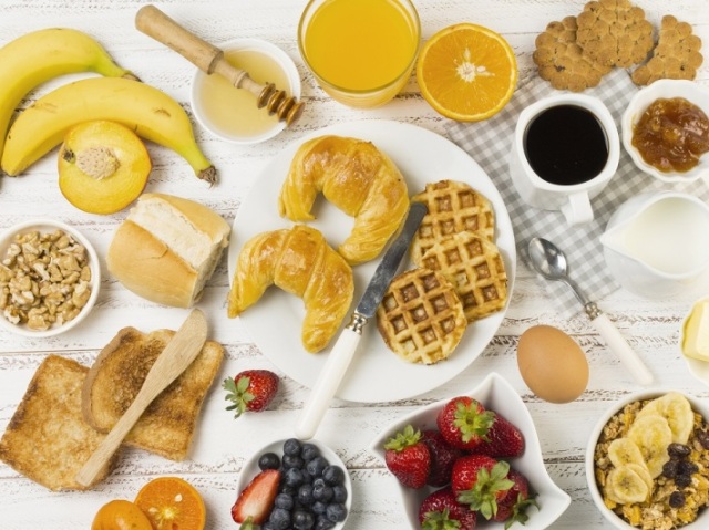 Café da manhã com frutas, pães, ovos , café e suco