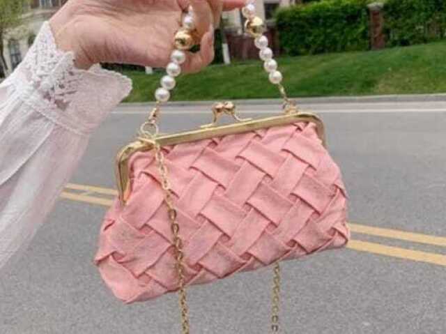 Bolsa rosa com alça dourada.